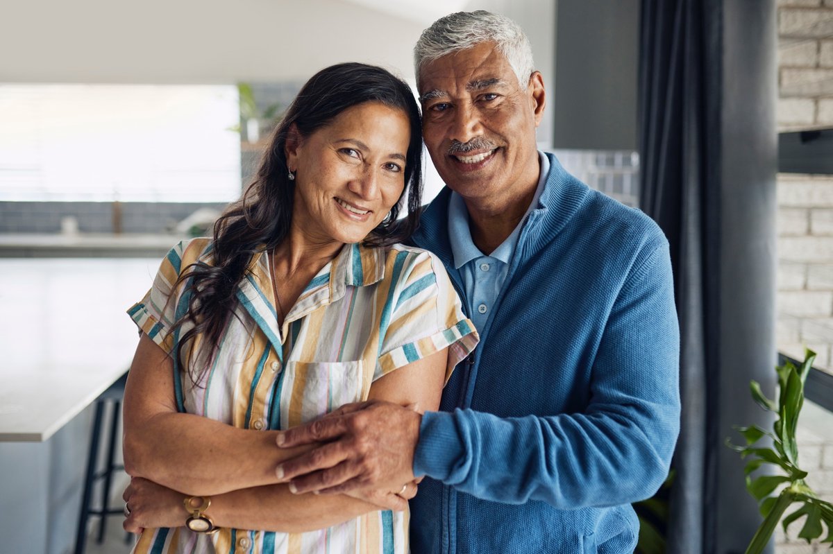 A man and woman hug each other in the kitchen.