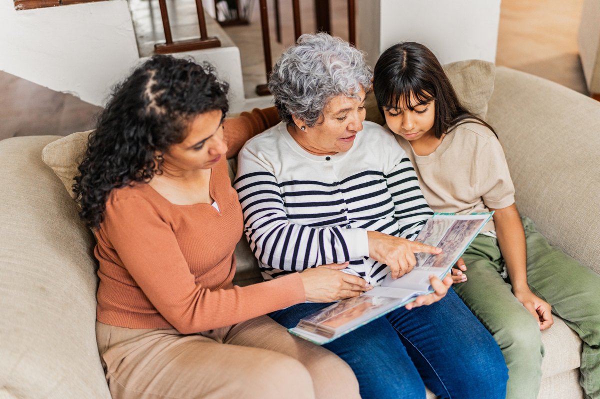 Grandmother reads on the couch with her daughter and granddaughter