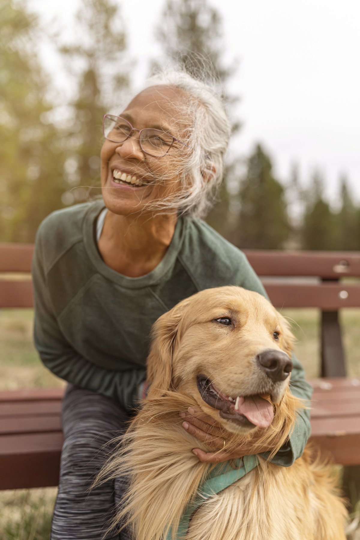 A happy woman outdoors with a golden retriever.