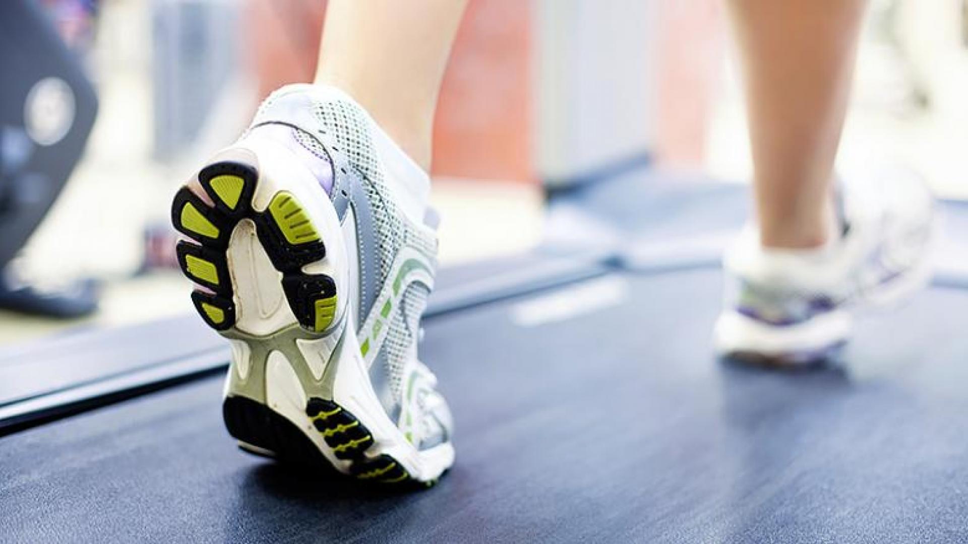 A person in sneakers walking on a treadmill.