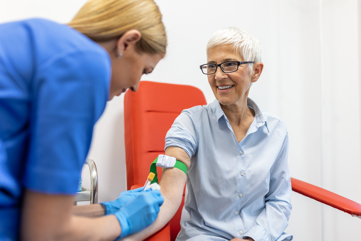 Medical technologist doing a blood draw services for patient. lab assistant with sterile rubber gloves taking blood sample from patient.