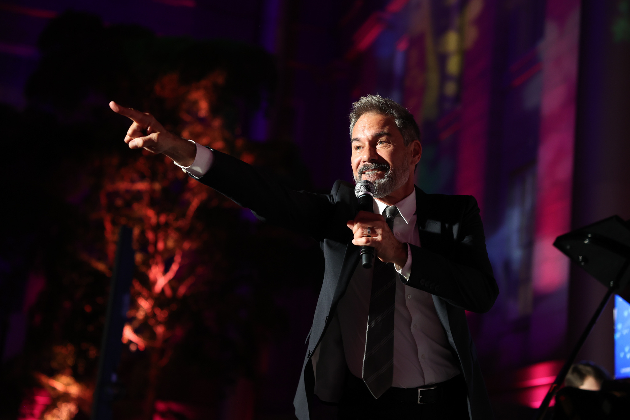 Eric McCormack on stage singing into a microphone.