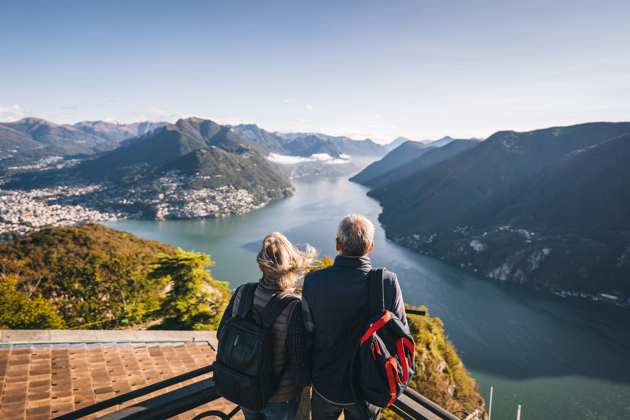 Senior couple relax at viewpoint and look off to distant scene.